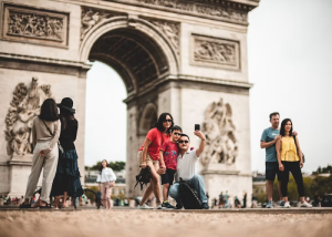 Tourists taking a selfie in front of a triumphal arch monument